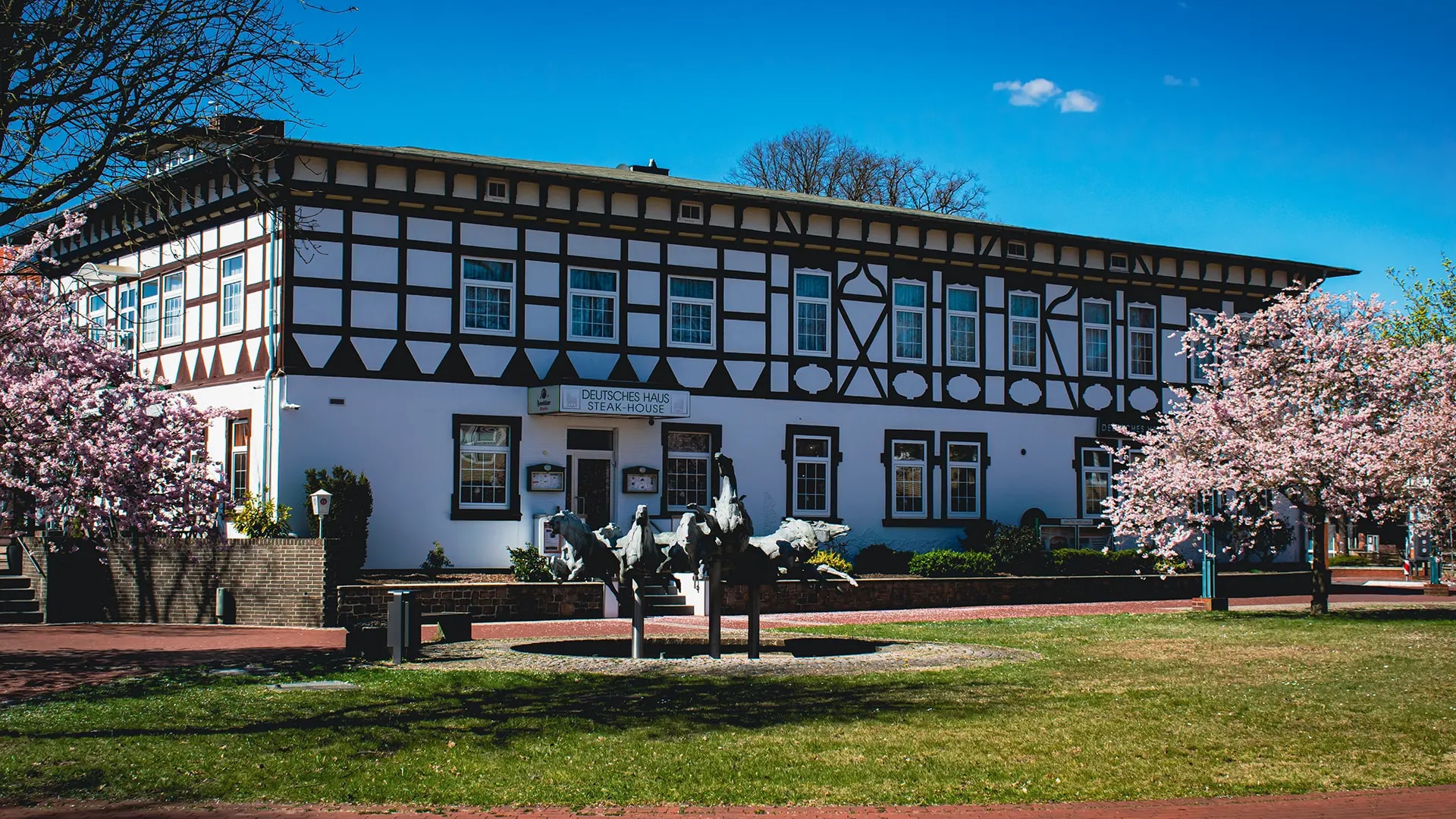 Fachwerkfassade des Hotels Deutsches Haus mit blühenden Bäumen