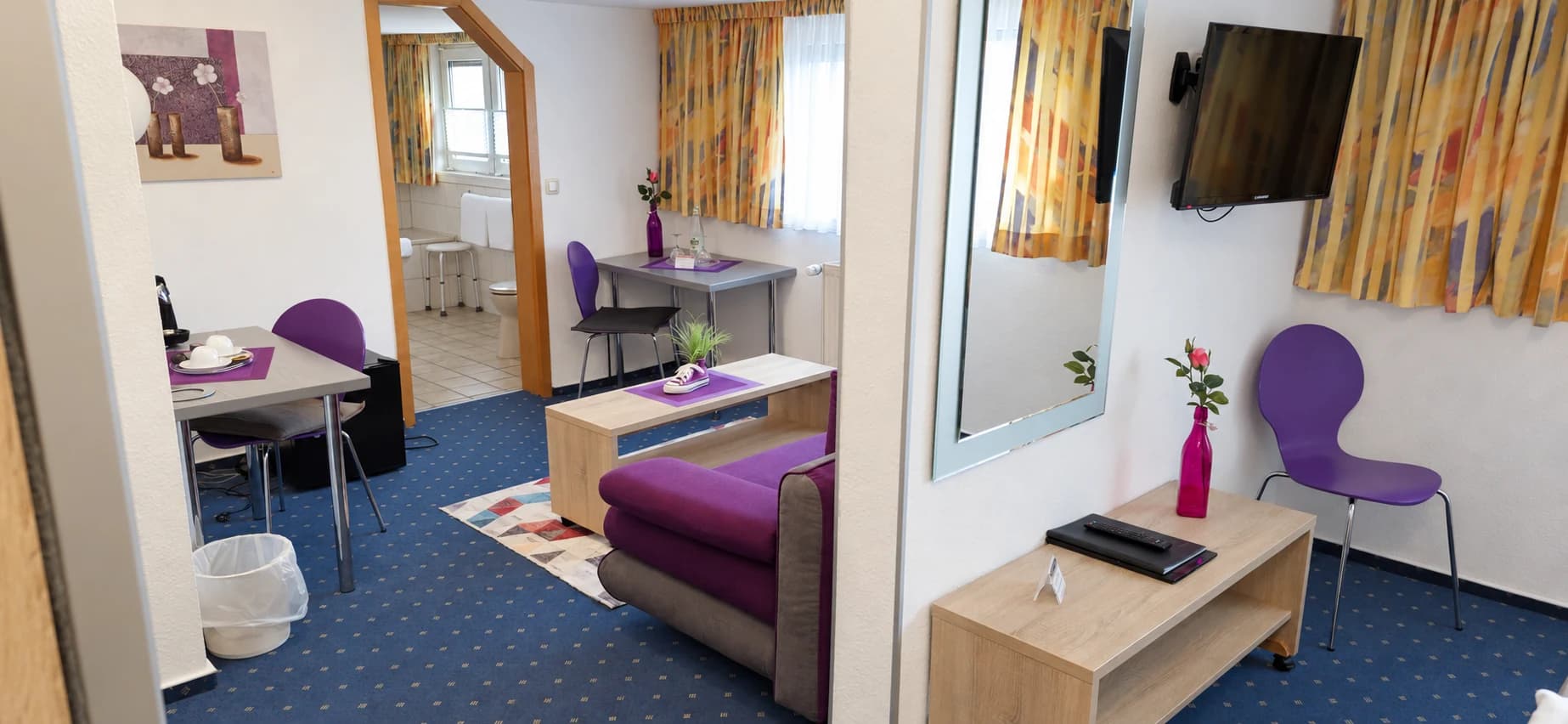 Wohnbereich der Familienunterkunft mit violettem Sofa und Sitzecke